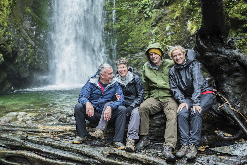 Four people sitting in front of waterfall